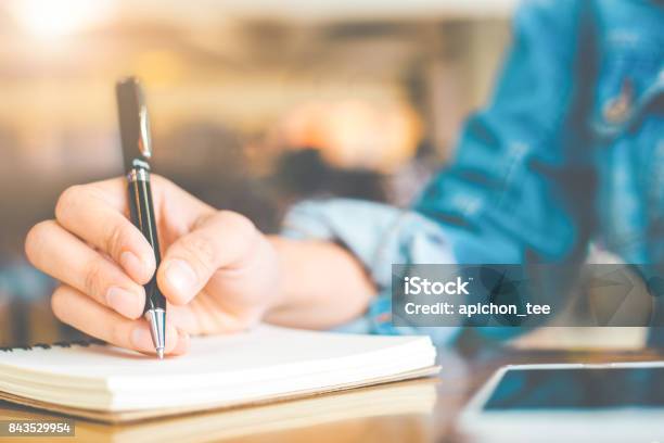 Zarte Frauenhand Schreiben Mit Einem Stift Auf Einem Hölzernen Schreibtisch Auf Einem Notizblock Stockfoto und mehr Bilder von Buch