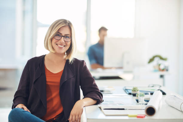 My career keeps me smiling everyday Portrait of a young woman working at her desk in a modern office blond hair stock pictures, royalty-free photos & images