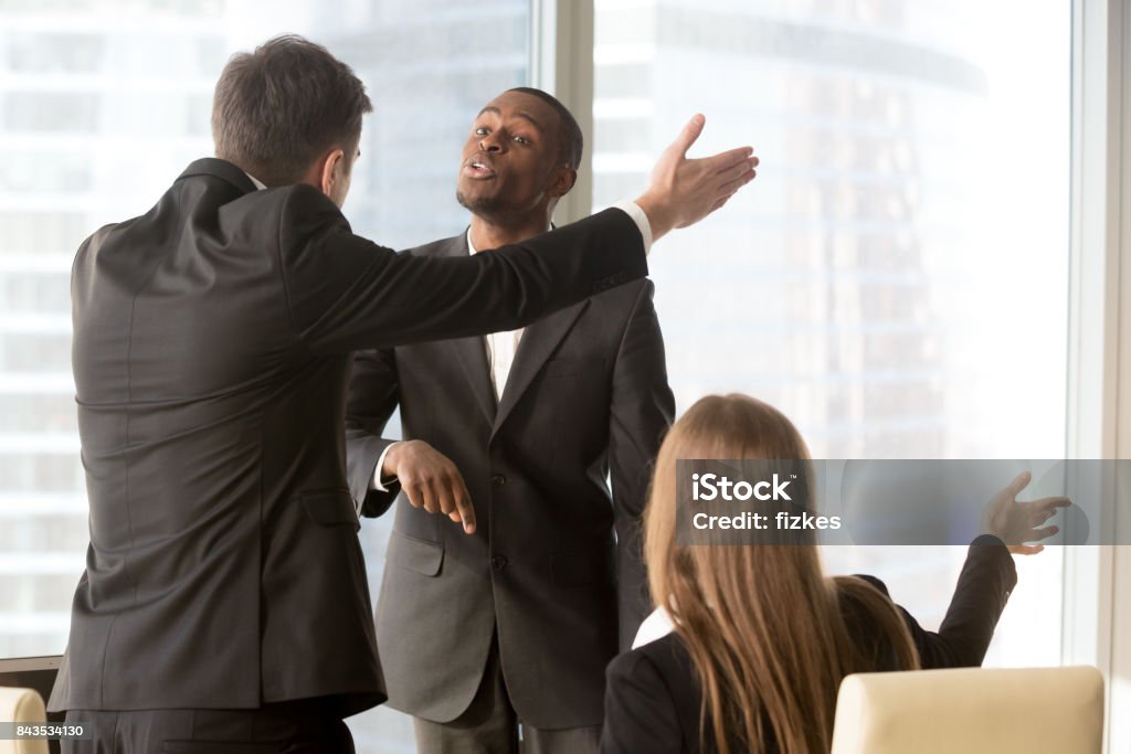 Annoyed business partners arguing during meeting Ambitious african american male candidate insisting on getting a job, male and female caucasian recruiters asking quarrelsome applicant to leave office. Failed interview, conflict at work or dismissal Business Stock Photo