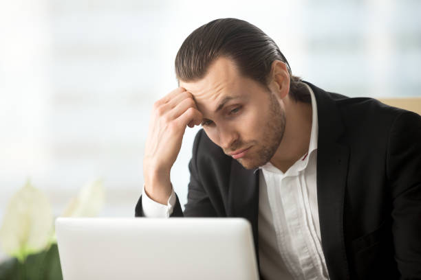 istock Puzzled young businessman looking at laptop screen at workplace. 843545434