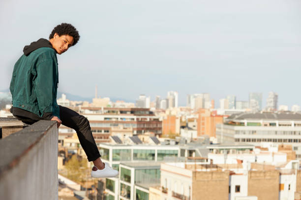 istock Portrait of young man sitting on retaining wall at rooftop 843548514