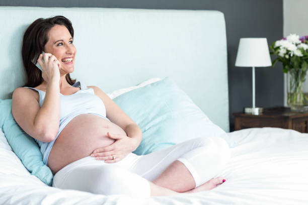istock Pregnant woman lying in bed making a phone call 843550580