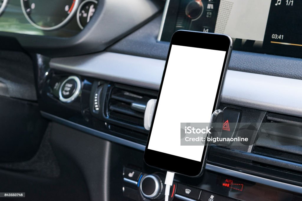 Smartphone in a car use for Navigate or GPS. Driving a car with Smartphone in holder. Mobile phone with isolatede white screen. Blank empty screen. copy space. Empty space for text. modern car interior details. Car Stock Photo