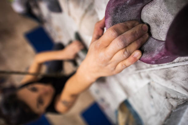 Close up of unrecognizable woman's hand during wall climbing in a health club.
