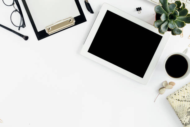 istock White tablet with clipboard, keyboard, notepad, glasses, succulents and cup of coffee. Office table desk. Top view 843554576