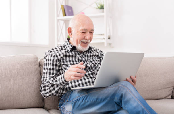 istock Smiling senior man reading news on laptop 843564276