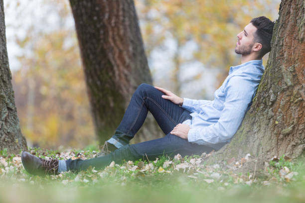 istock Handsome sad man in the park. Autumn scenery 843570040