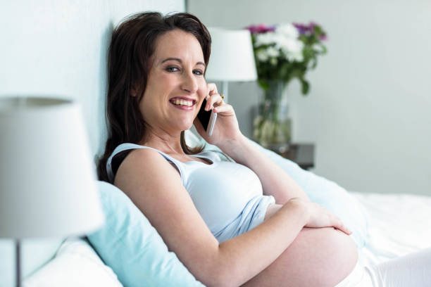 istock Pregnant woman lying in bed making a phone call 843572968