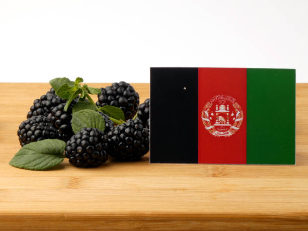 istock Afghanistan flag on a wooden panel with blackberries isolated on a white background 843577678