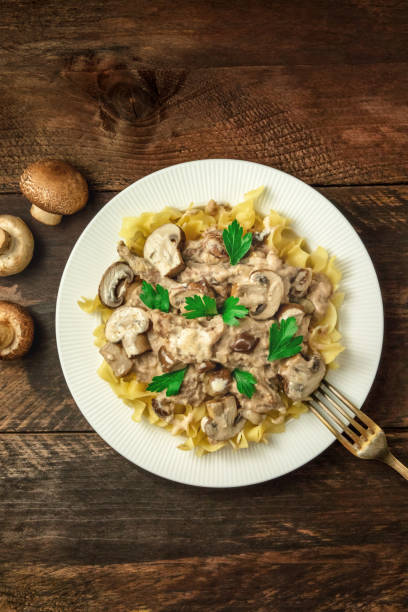 Mushroom beef stroganoff with egg pasta and copy space Mushroom beef stroganoff, served with the typical egg pasta, with cremini and champignons, with a fork, shot from above on a dark rustic texture with a place for text Cepe stock pictures, royalty-free photos & images