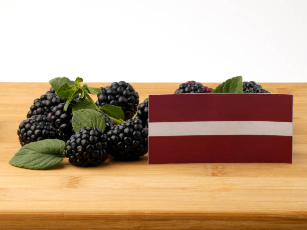 istock Latvia flag on a wooden panel with blackberries isolated on a white background 843580952