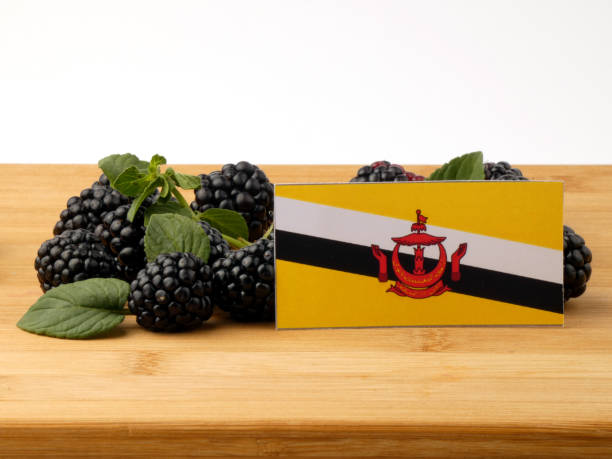 istock Brunei flag on a wooden panel with blackberries isolated on a white background 843582188