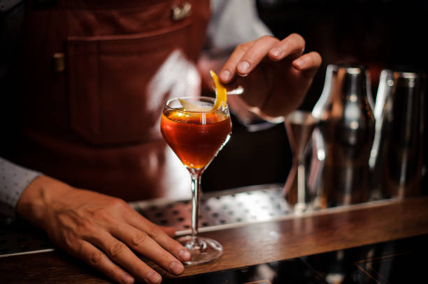 istock Bartender with glass and lemon peel preparing cocktail at bar 843586178
