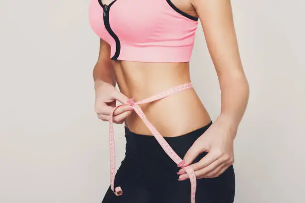Photo of Fit woman measuring her waist closeup
