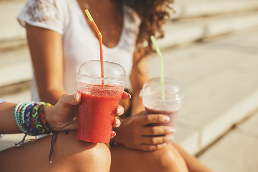 Female hand holding red smoothie.