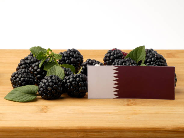 istock Qatari flag on a wooden panel with blackberries isolated on a white background 843591370