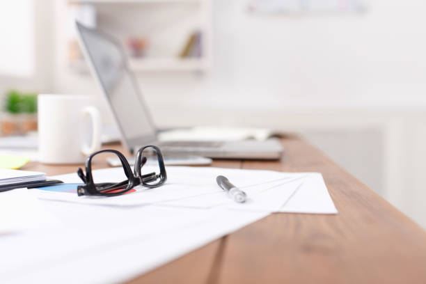 side view of office desk with glasses, laptop and other items - paper document notebook laptop imagens e fotografias de stock