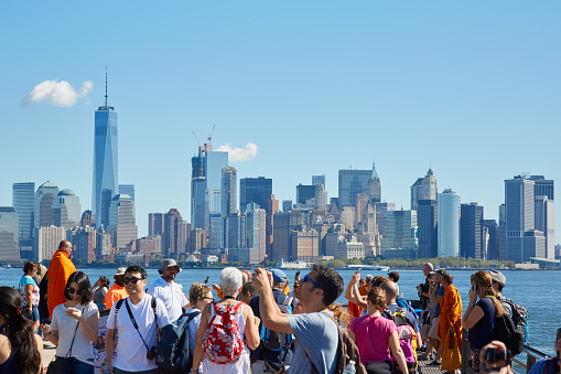 New York - September 12, 2016: People and tourists shooting photos and looking at New York city skyline from Liberty island in a sunny day in New York.