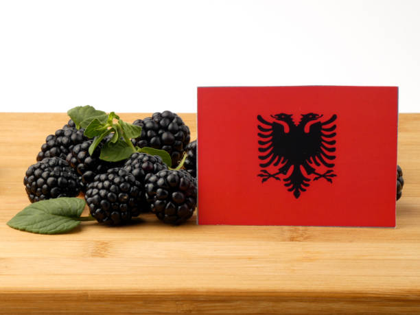 istock Albanian flag on a wooden panel with blackberries isolated on a white background 843599510