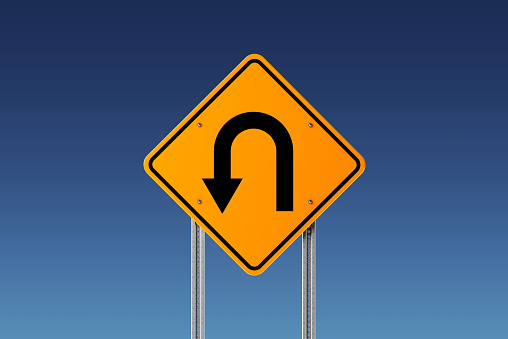Yellow U Turn raffic sign on blue sky. Horizontal composition with copy space. Clipping path is included.