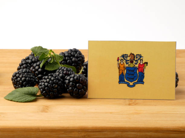 istock New Jersey flag on a wooden panel with blackberries isolated on a white background 843603814