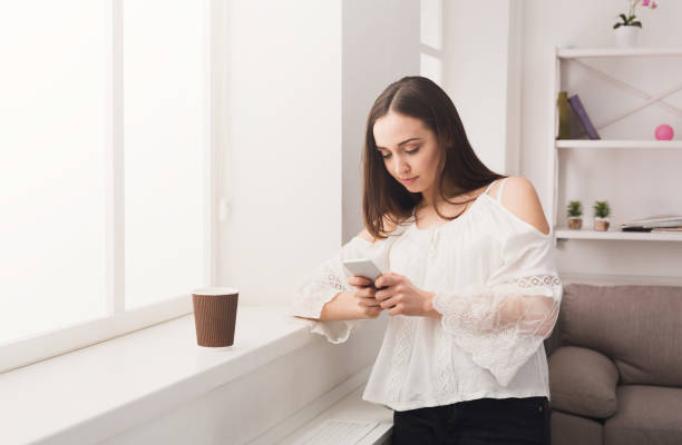 istock Online. Young woman messaging on mobile phone 843603872