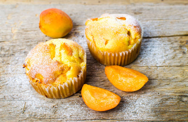 Homemade apricot muffins with fruit on a wooden table