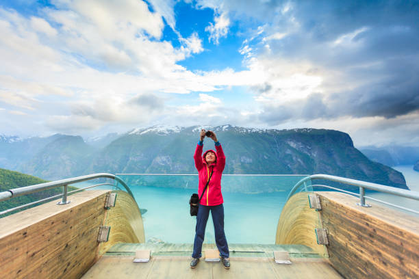 Tourist photographer with camera on Stegastein lookout, Norway Tourism and travel. Woman tourist nature photographer taking photo with camera, enjoying Aurland fjord landscape from Stegastein lookout, Norway Scandinavia. stegastein viewpoint stock pictures, royalty-free photos & images