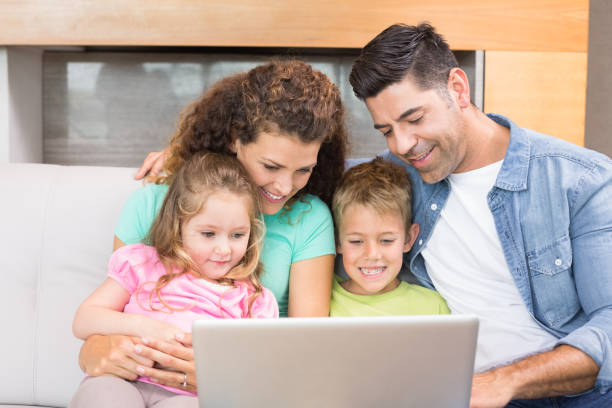 istock Happy family sitting on sofa using laptop together 843621008