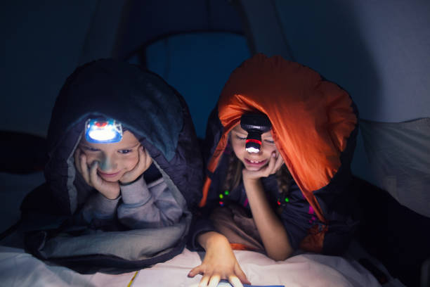 istock Children reading a book on camping at night 843622500