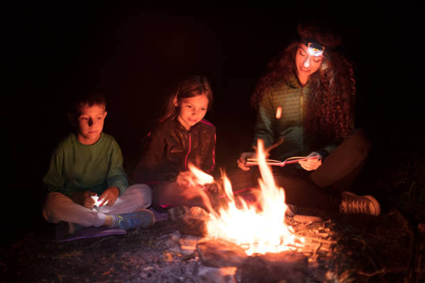 Family sitting around the cam fire at dusk in nature in having a fun