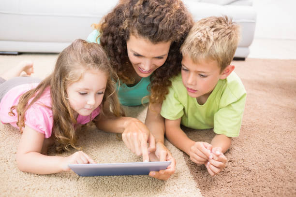 istock Happy siblings lying on the rug using tablet with their mother 843623628