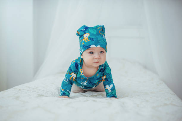 nouveau-né vêtu d’un costume vert, allongé sur un lit douillet dans un studio de blanc. - newborn little girls baby lying down photos et images de collection