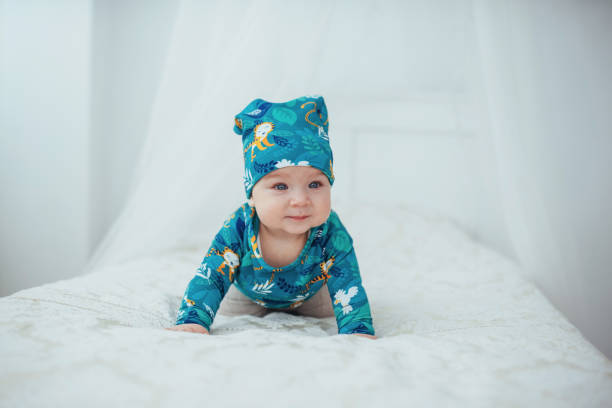 nouveau-né vêtu d’un costume vert, allongé sur un lit douillet dans un studio de blanc. - newborn little girls baby lying down photos et images de collection