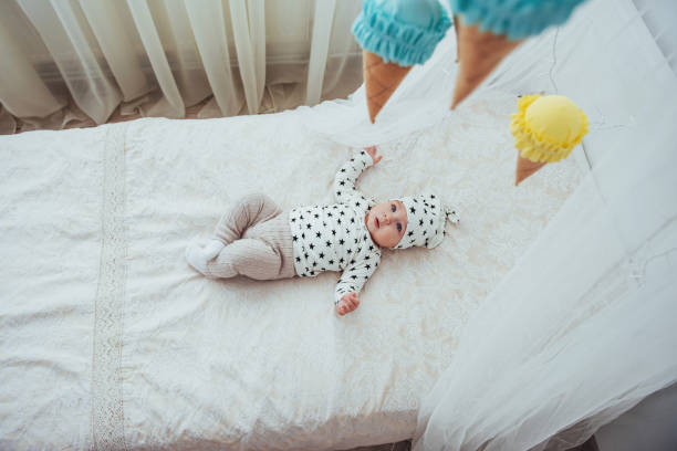 nouveau-né, vêtu d’un costume blanc et d’étoiles noires est un blanc moelleux lit dans le studio - newborn little girls baby lying down photos et images de collection