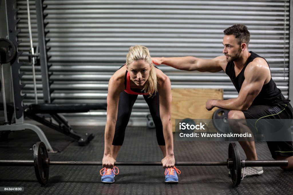 Trainer helping woman with lifting barbell Trainer helping woman with lifting barbell at gym 25-29 Years Stock Photo