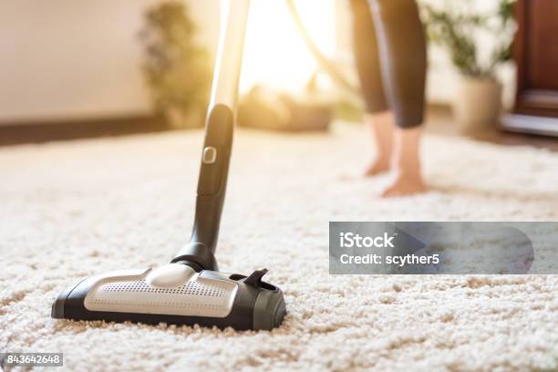 Woman Using A Vacuum Cleaner While Cleaning Carpet In The House Stock Photo - Download Image Now
