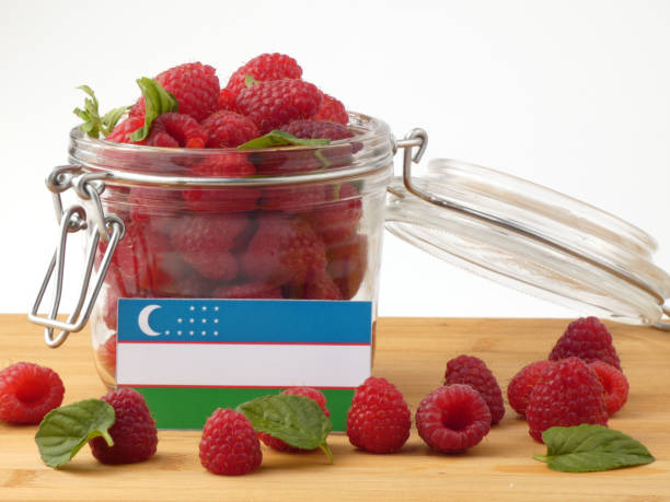 istock Uzbekistan flag on a wooden panel with raspberries isolated on a white background 843656762