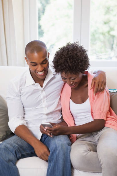 istock Happy couple relaxing on the couch with smartphone 843657416