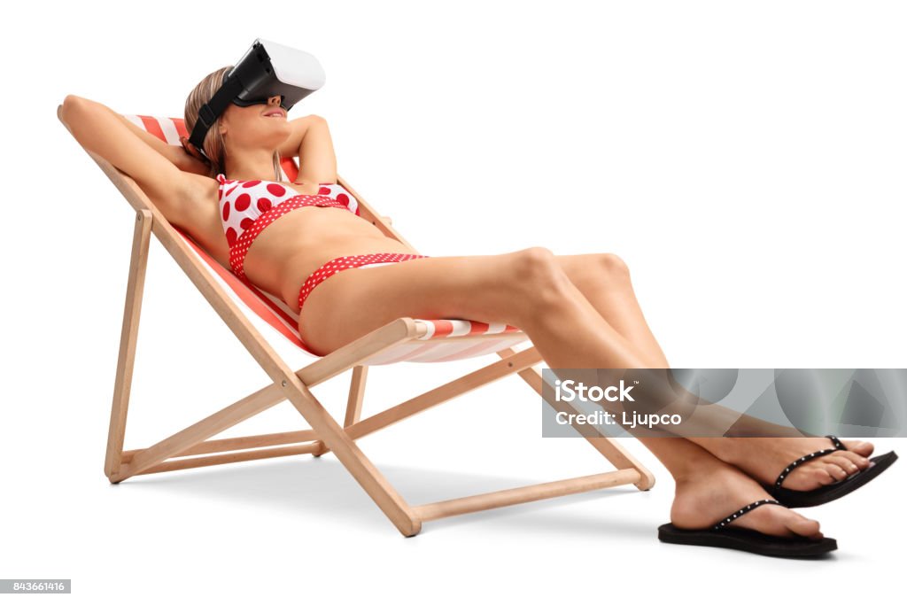 Young woman with a VR headset lying in a deck chair Young woman with a VR headset lying in a deck chair isolated on white background Deck Chair Stock Photo