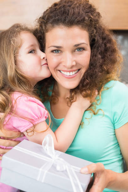 istock Smiling mother getting a kiss and a present from her daughter 843666344