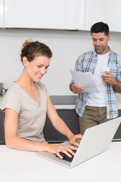 istock Happy woman using laptop while partner reads the newspaper 843672500