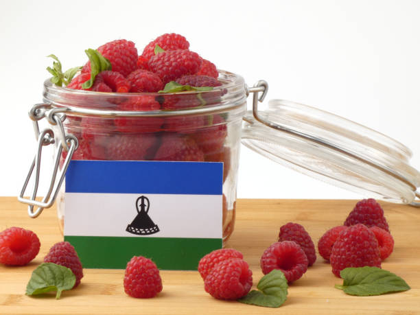 istock Lesotho flag on a wooden panel with raspberries isolated on a white background 843672980