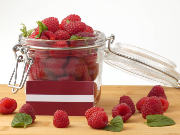 istock Latvia flag on a wooden panel with raspberries isolated on a white background 843675918