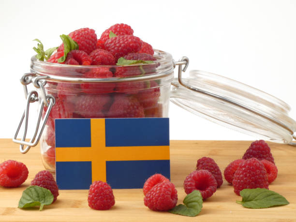 istock Swedish flag on a wooden panel with raspberries isolated on a white background 843678022