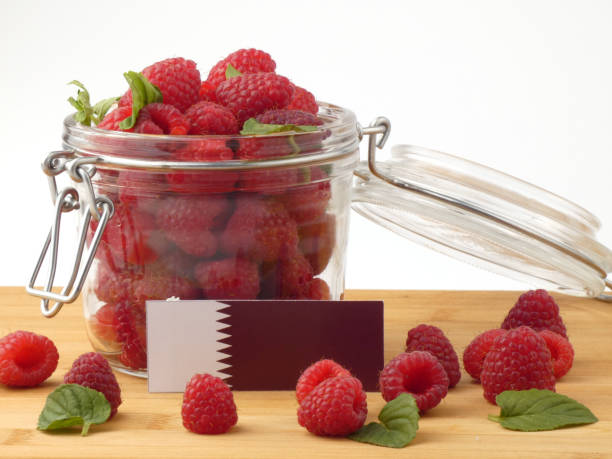 istock Qatari flag on a wooden panel with raspberries isolated on a white background 843678366