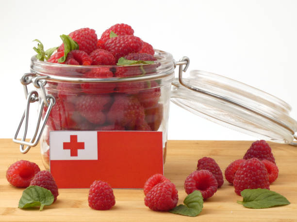 Tongan flag on a wooden panel with raspberries isolated on a white background