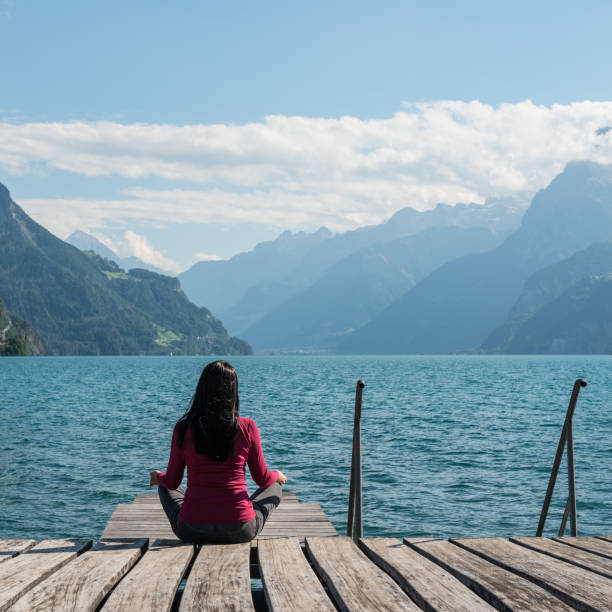 istock Woman meditating sitting on the lake shore. 843696024