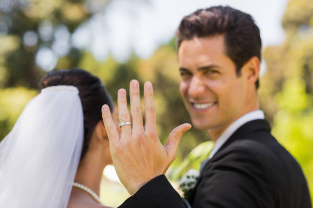 istock Bridegroom showing wedding ring to the camera in park 843717070
