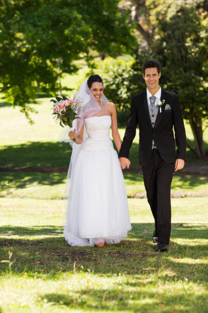 istock Newlywed couple holding hands and walking in park 843717112